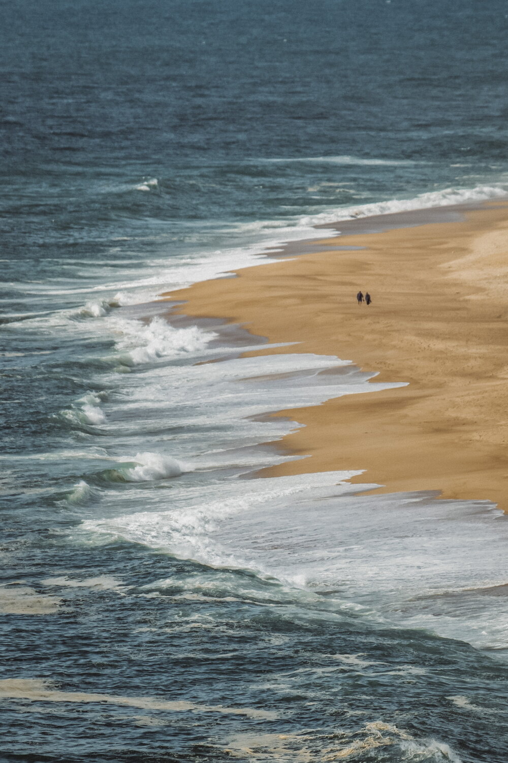 Zwei Spaziergänger am Strand von Nazaré