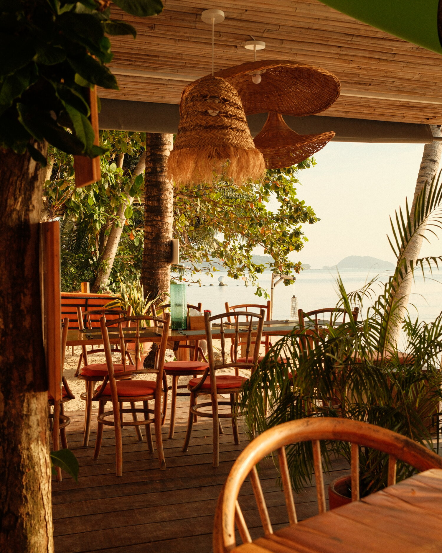 Terraza de café con lámparas de ratán frente al mar