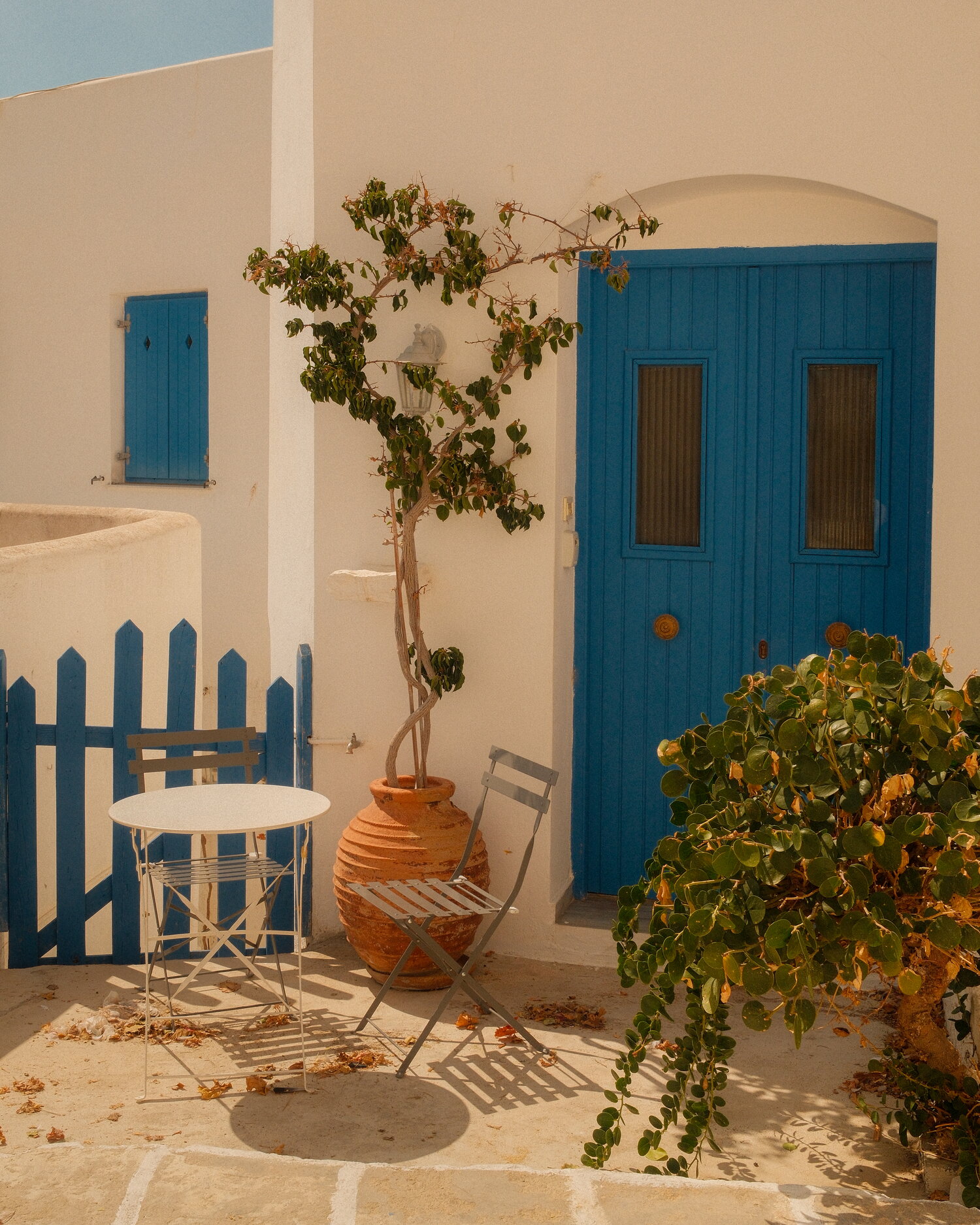 Blue door, bistro chairs and a clay pot