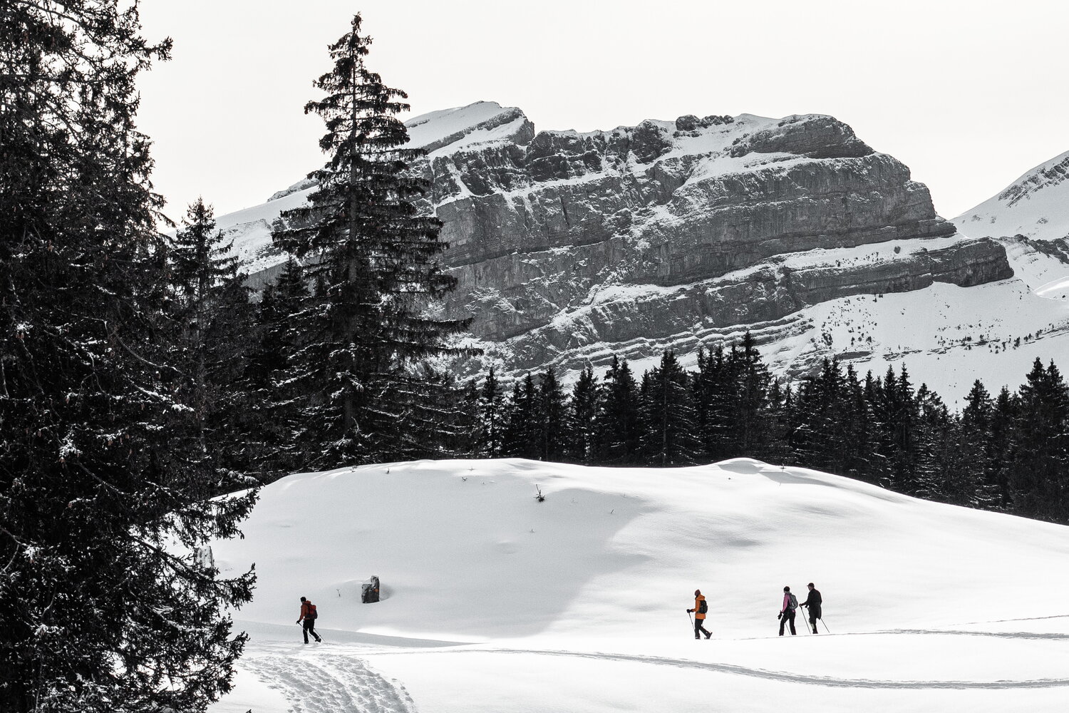 Hikers beneath a layered rock wall