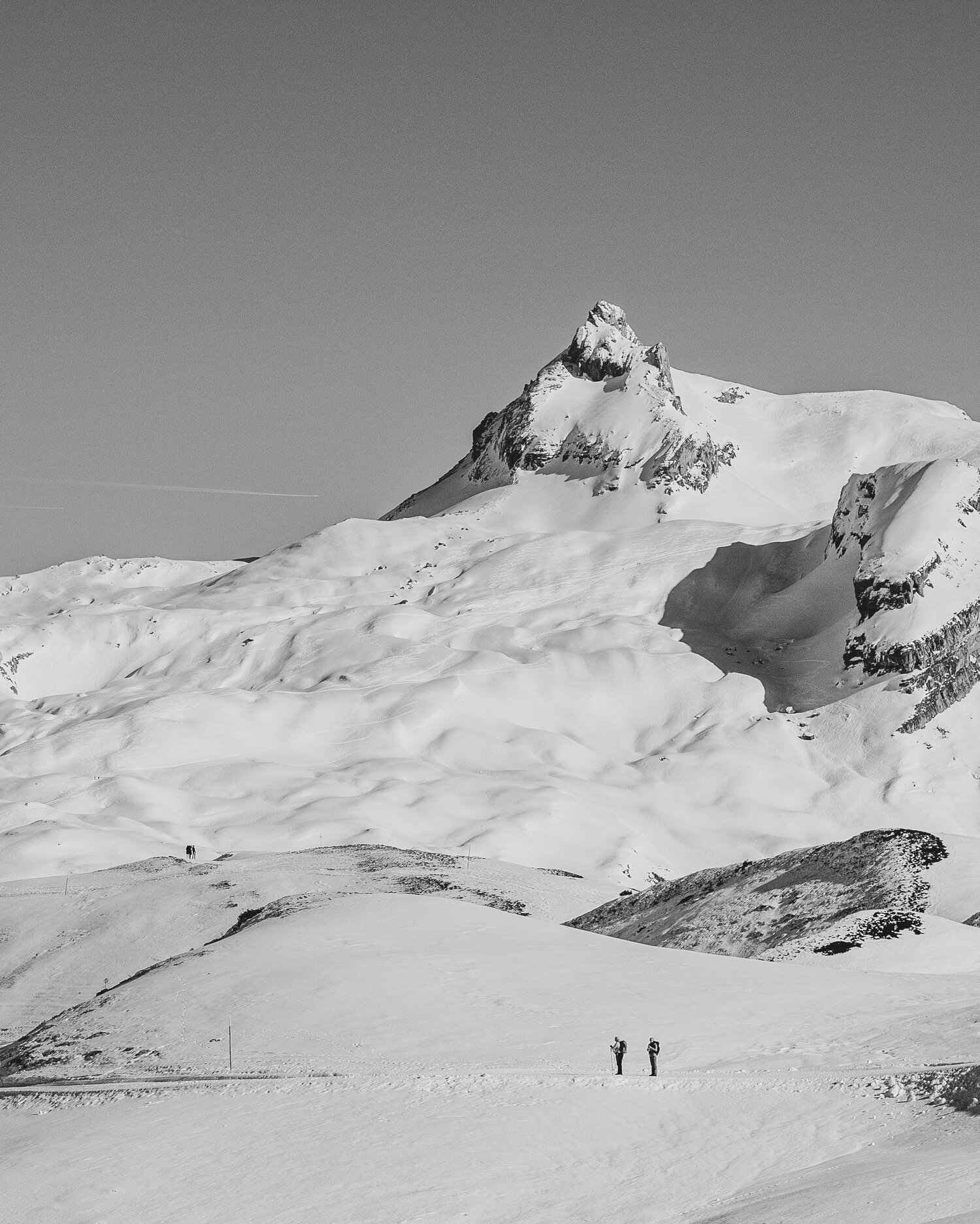 Schwarzweißer Gipfel über zwei Winterwanderern