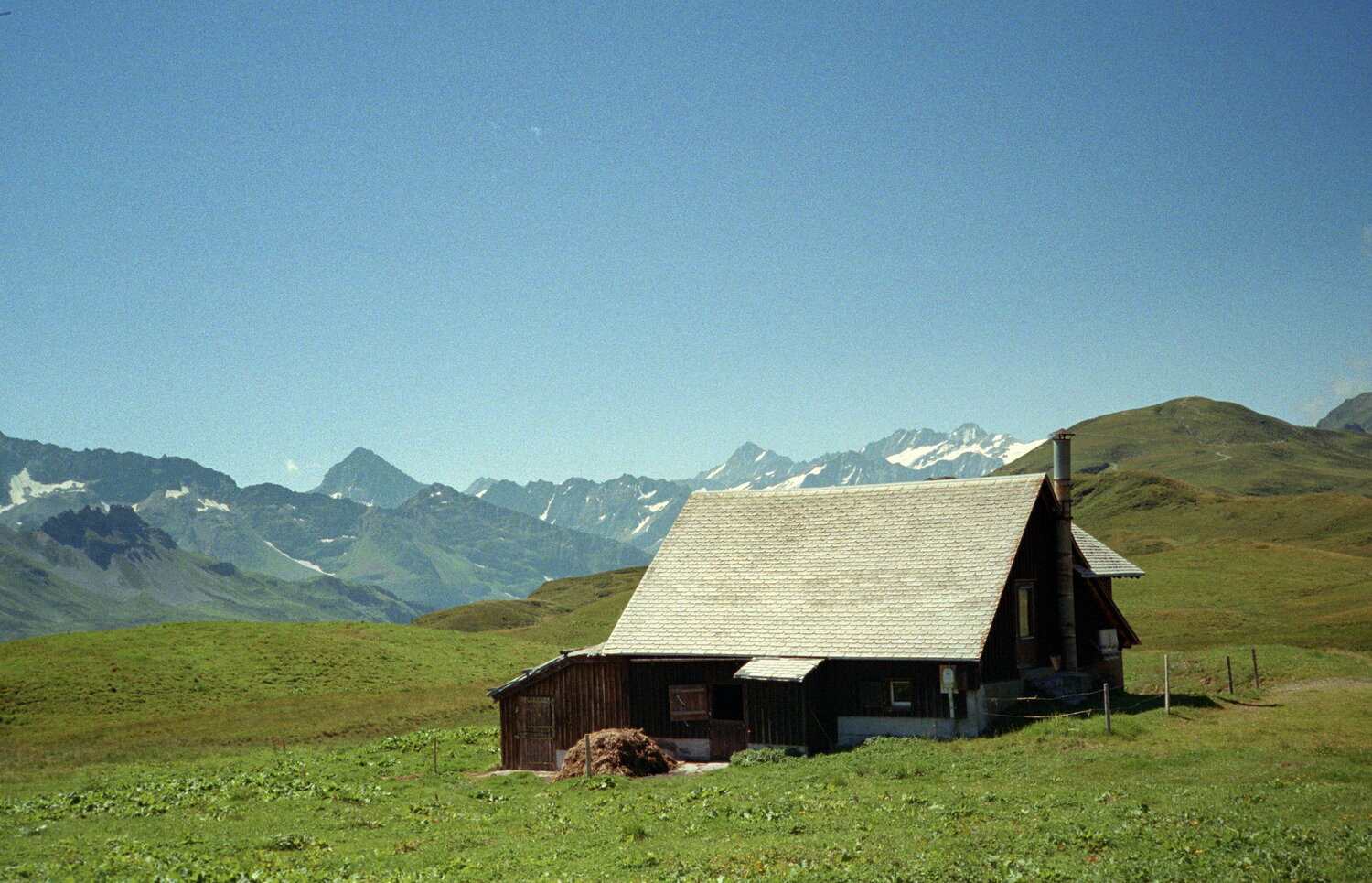 Eine einsame Almhütte vor einer fernen Bergkette