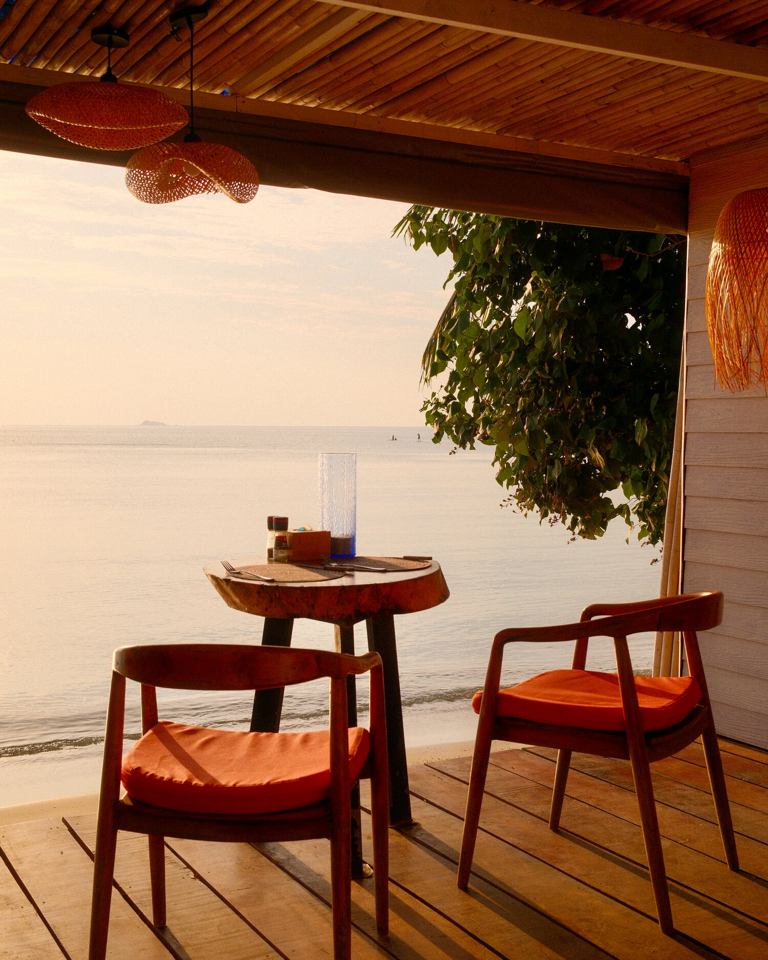 Dos sillas en una terraza de madera junto al mar al atardecer
