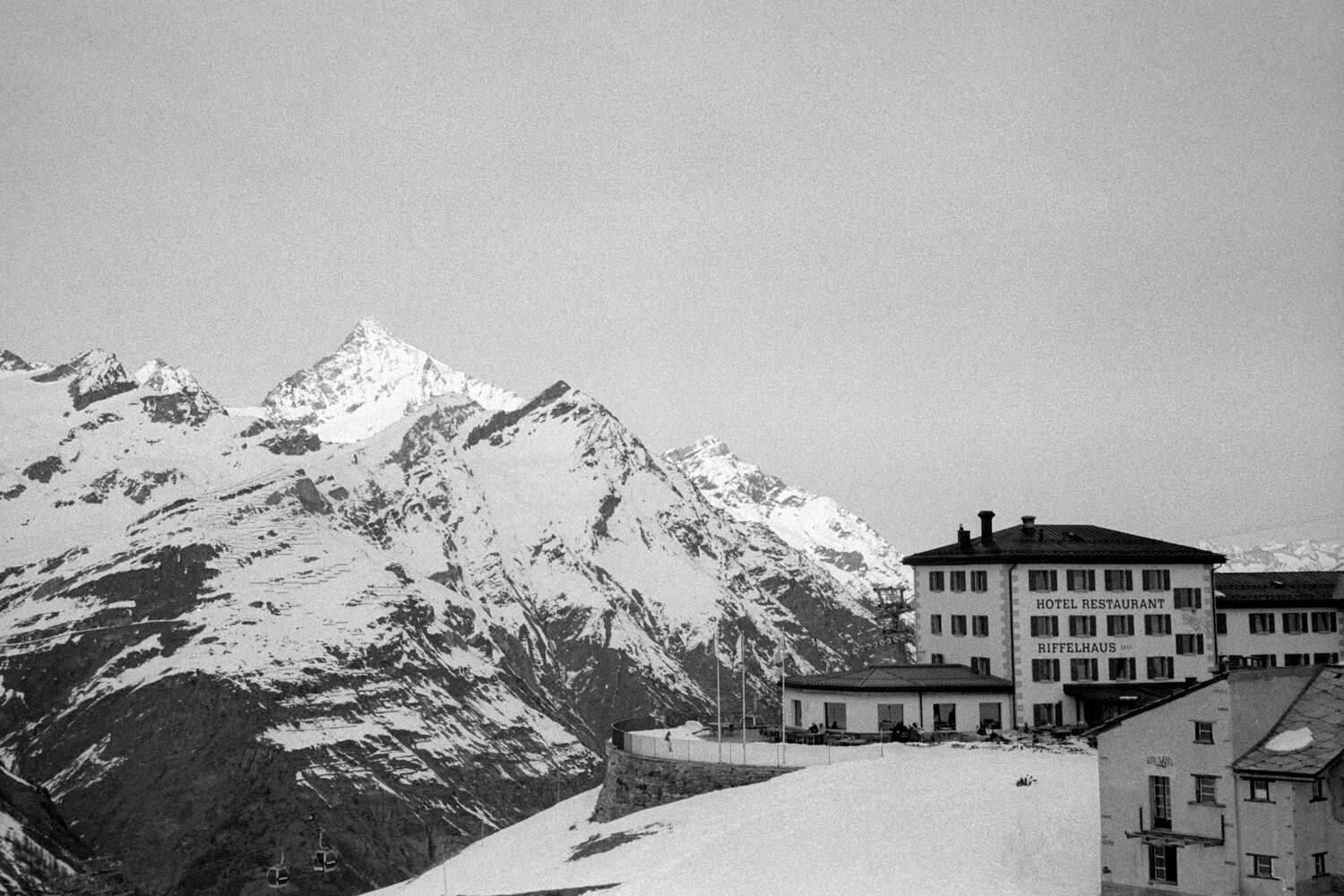 A mountain hotel and snowy peaks in black and white