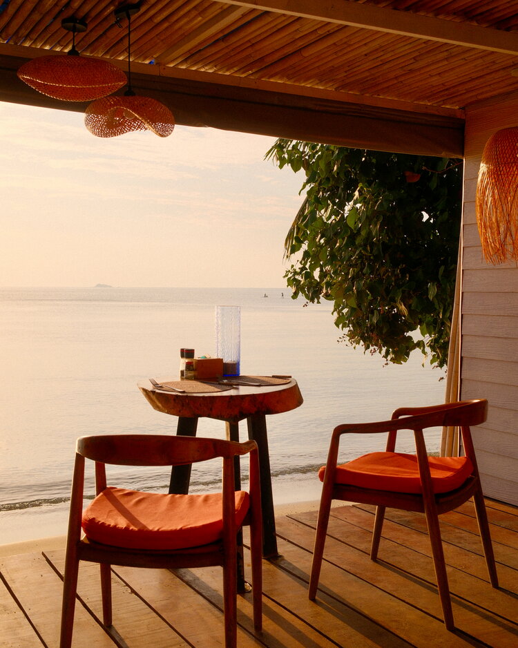 Dos sillas en una terraza de madera junto al mar al atardecer